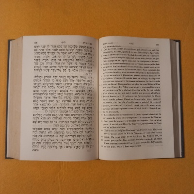 Livro aberto com texto em hebraico e francês sobre fundo amarelo