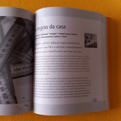 Livro aberto com texto em português sobre regras da casa e imagem de fitas métricas em preto e branco