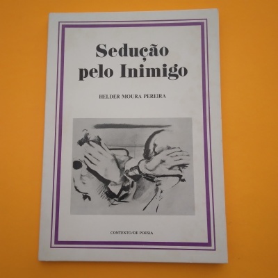 Capa de livro branca com moldura roxa e título 'Sedução pelo Inimigo' com imagem de mãos acorrentadas