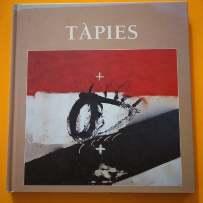 Livro com capa abstrata em vermelho, branco e preto com o título TÀPIES