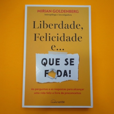 Livro 'Liberdade, Felicidade e... QUE SE F#DA!' de Mirian Goldenberg sobre fundo laranja
