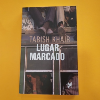 Capa de livro 'LUGAR MARCADO' de Tabish Khair com imagem de pessoas e autocarro
