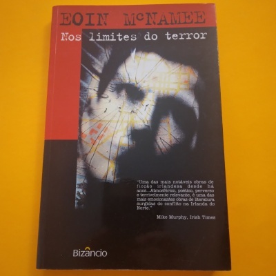 Capa de livro preto e vermelho com texto e rosto desfocado e rachado