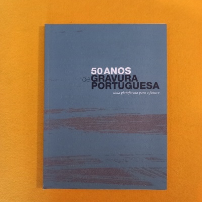 Livro azul com texto '50 ANOS GRAVURA PORTUGUESA uma plataforma para o futuro' sobre fundo laranja