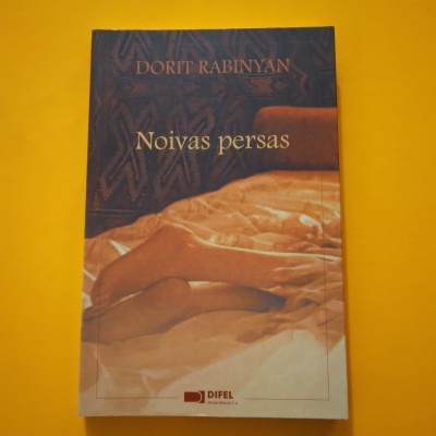 Capa do livro 'Noivas persas' de Dorit Rabinyan com cama e lençóis em tons castanhos