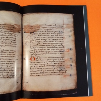 Livro antigo aberto com texto manuscrito em tinta preta e vermelha