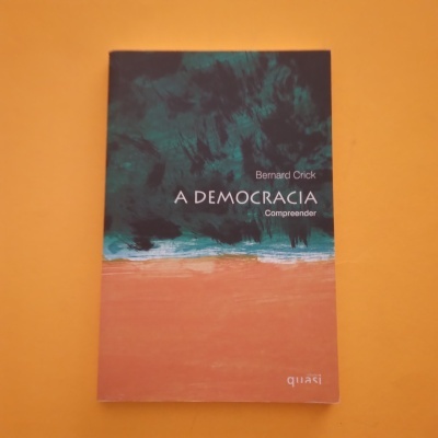 Livro A DEMOCRACIA de Bernard Crick com capa azul escuro e castanho sobre fundo amarelo