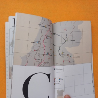 Mapa de rotas ferroviárias em livro aberto com fundo laranja