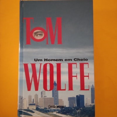 Capa de livro 'Um Homem em Cheio' de Tom Wolfe com imagem de cidade ao fundo