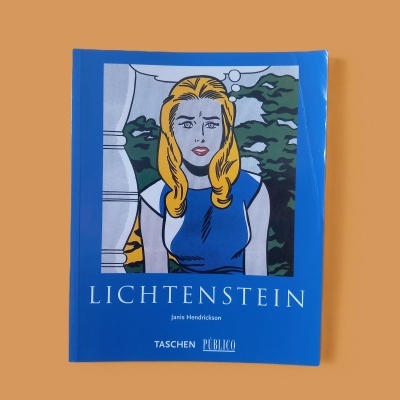 Livro azul com capa ilustrada em estilo pop art com mulher loira