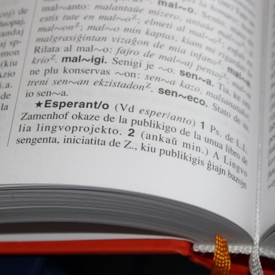 Página aberta de livro com texto em esperanto e fita marcador laranja