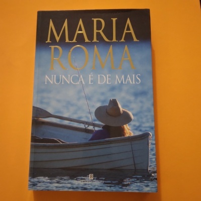 Capa do livro 'NUNCA É DE MAIS' de Maria Roma com pessoa de chapéu numa embarcação sobre a água