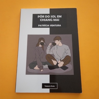 Capa de livro 'Pôr do Sol em Chiang Mai' com ilustração de dois jovens a beber e fundo laranja