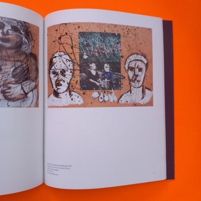 Página de livro aberto com pintura de rostos e imagem colorida central