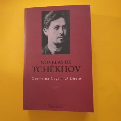 Capa de livro vermelha com foto de Anton Tchékhov e texto Novelas de Tchékhov, Drama na Caça, O Duelo.