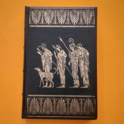 Livro preto com ilustrações brancas de figuras clássicas e cão sobre fundo laranja