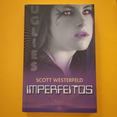 Capa de livro 'Im perfeitos' de Scott Westerfeld com rosto de jovem mulher e fundo roxo