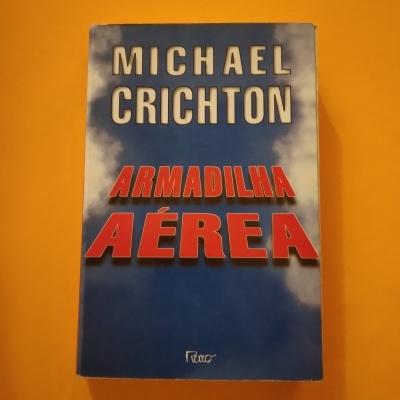Livro 'Armadilha Aérea' de Michael Crichton com capa azul e nuvens