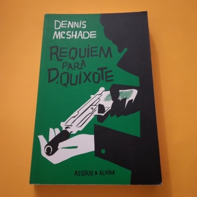 Livro verde e preto com título e ilustração de mão segurando arma.