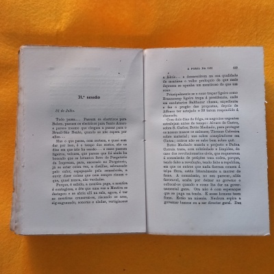 Livro aberto com texto impresso em português sobre fundo laranja