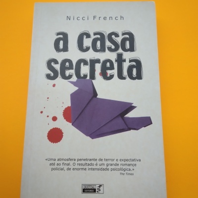 Capa do livro 'a casa secreta' de Nicci French com origami roxo e manchas vermelhas
