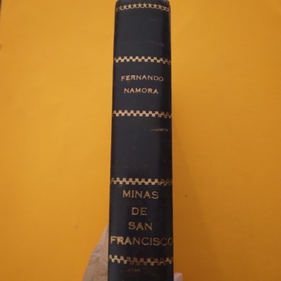 Livro com lombada azul e texto dourado sobre fundo amarelo