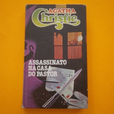 Capa de livro 'Assassinato na Casa do Pastor' de Agatha Christie com faca e selo sobre fundo amarelo.