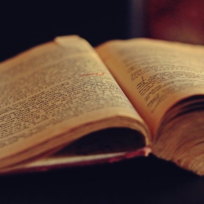 Livro antigo aberto com páginas amareladas sobre superfície escura