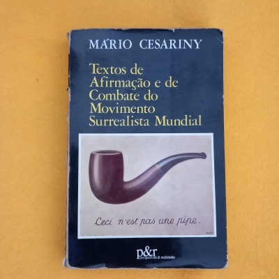 Livro 'Textos de Afirmação e de Combate do Movimento Surrealista Mundial' com capa preta e imagem de cachimbo
