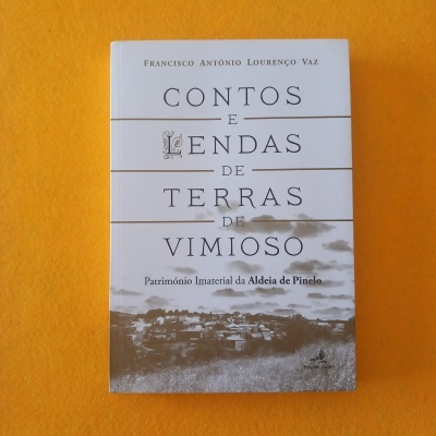 Livro Contos e Lendas de Terras de Vimioso sobre fundo almofadado laranja