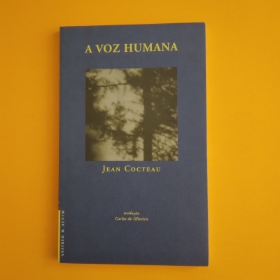 Livro azul A Voz Humana de Jean Cocteau sobre fundo laranja