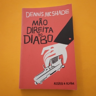 Livro vermelho com ilustração de mão segurando arma e texto na capa