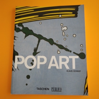 Livro POP ART com design colorido sobre superfície amarela