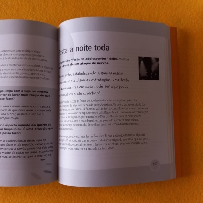 Livro aberto com texto em português numa superfície laranja