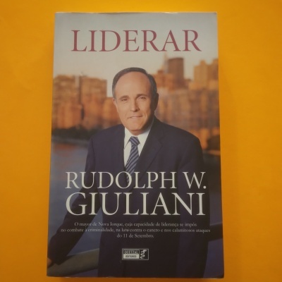 Capa de livro 'LIDERAR' de Rudolph W. Giuliani com fotografia do autor em fato e gravata, fundo de edifícios desfocado