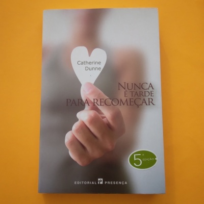 Capa de livro com mão segurando coração de papel, título e selo de edição