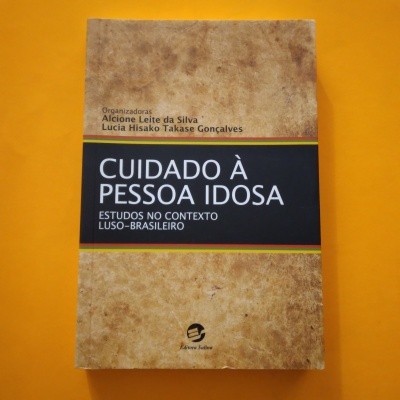 Livro Cuidado à Pessoa Idosa com capa castanha e faixa preta sobre fundo amarelo