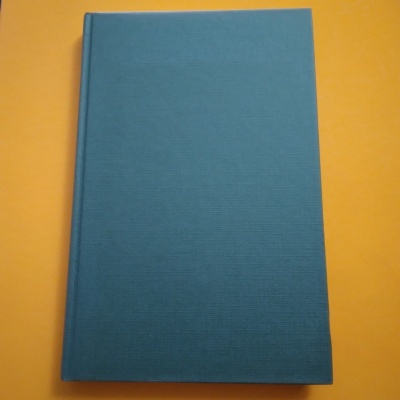 Livro com capa dura de tecido azul sobre fundo amarelo