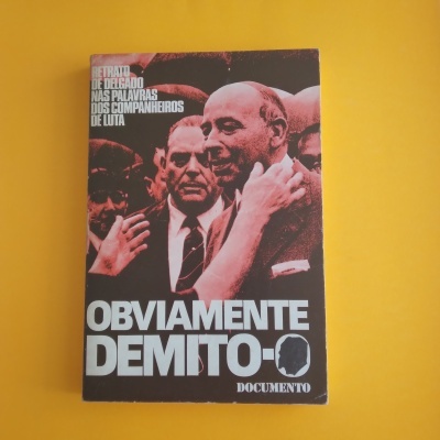 Livro preto e vermelho com texto OBVIAMENTE DEMITO e imagem de homens em traje formal num fundo amarelo