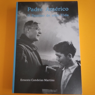 Capa do livro 'Padre Américo O Destino de uma Vida' com foto de homem e jovem em preto e branco sobre mesa amarela