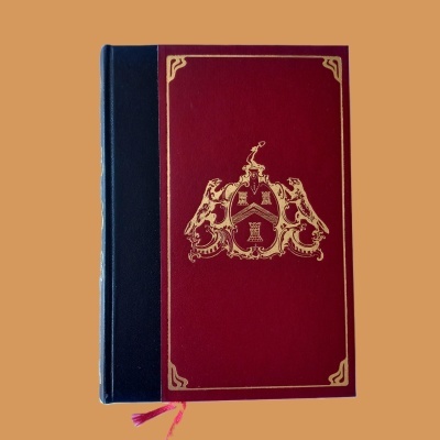 Livro capa dura vermelha com brasão dourado e lombada preta