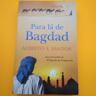 Capa do livro 'Para lá de Bagdad' com figura de homem de turbante azul e camelos no deserto