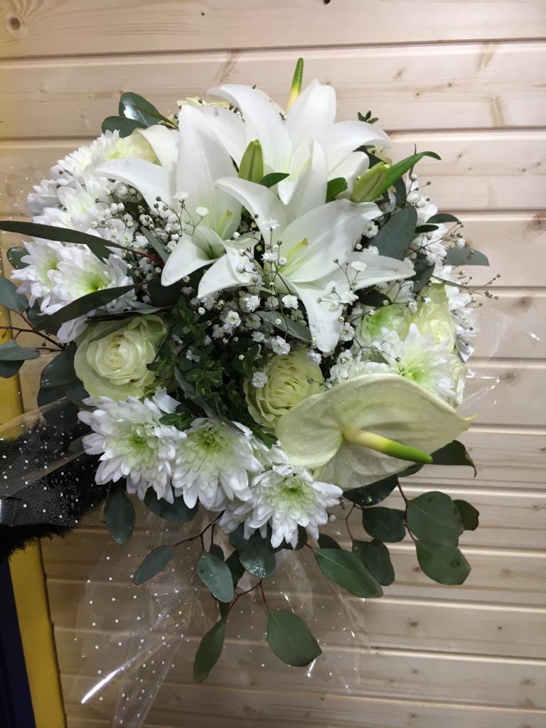 Buquê de flores brancas com lírios, crisântemos, rosas e folhagem em fundo de madeira clara