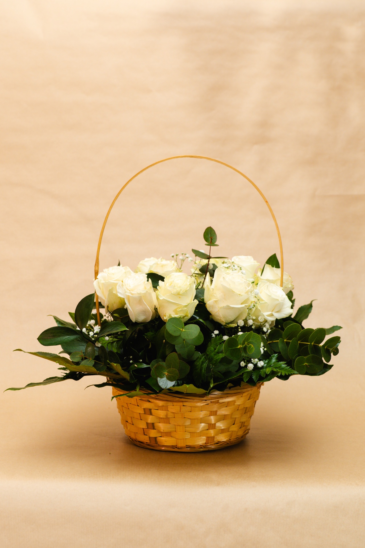 Cesto de flores brancas com folhas verdes em fundo bege