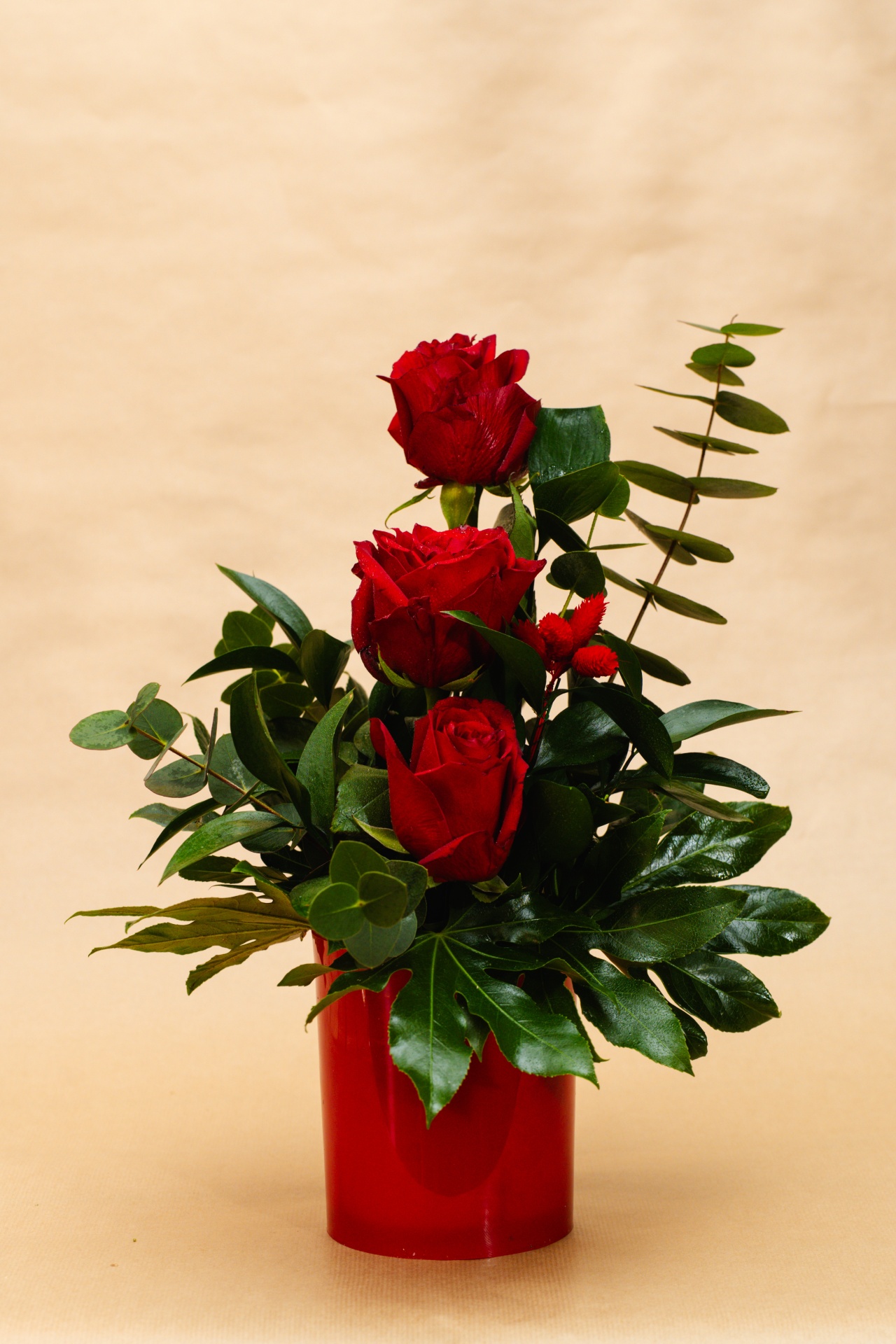 Arranjo de três rosas vermelhas com folhagens em vaso vermelho