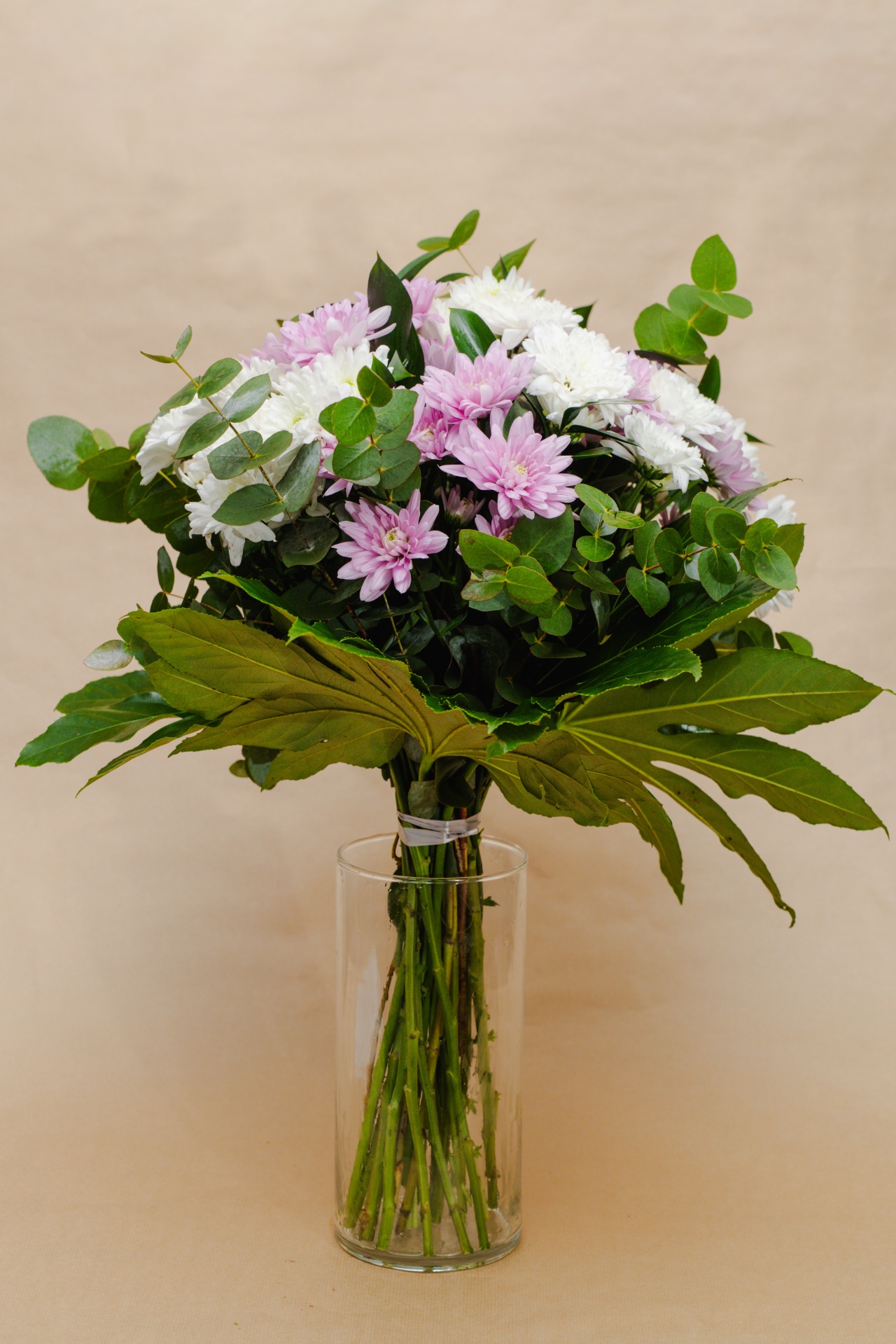Bouquet de flores brancas e lilases com folhas verdes em vaso transparente