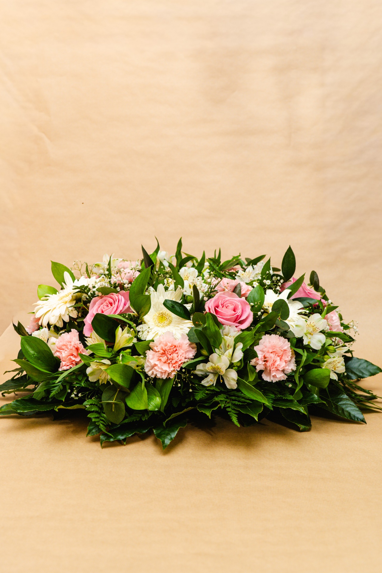 Arranjo floral com rosas cor-de-rosa, crisântemos brancos e folhagem verde.