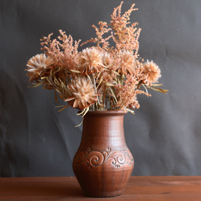 Jarro de cerâmica com flores secas em fundo cinzento escuro
