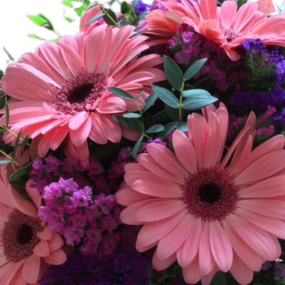 Bouquet de flores com gerberas cor-de-rosa e flores roxas com folhas verdes
