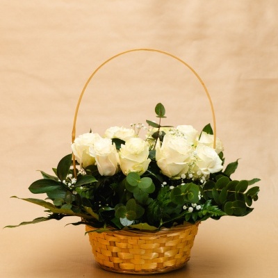 Cesto de flores brancas com folhas verdes em fundo bege